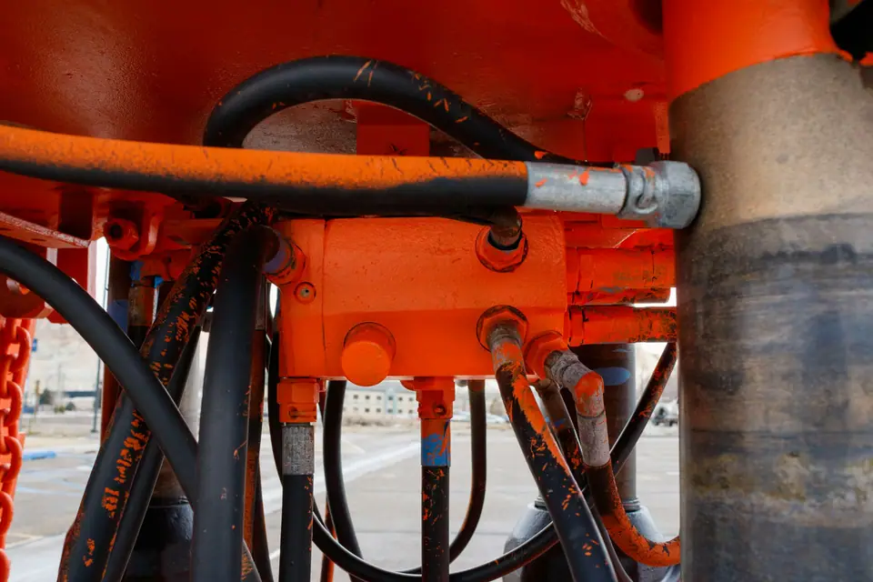 Hydraulic hoses connected to an orange hydraulic block