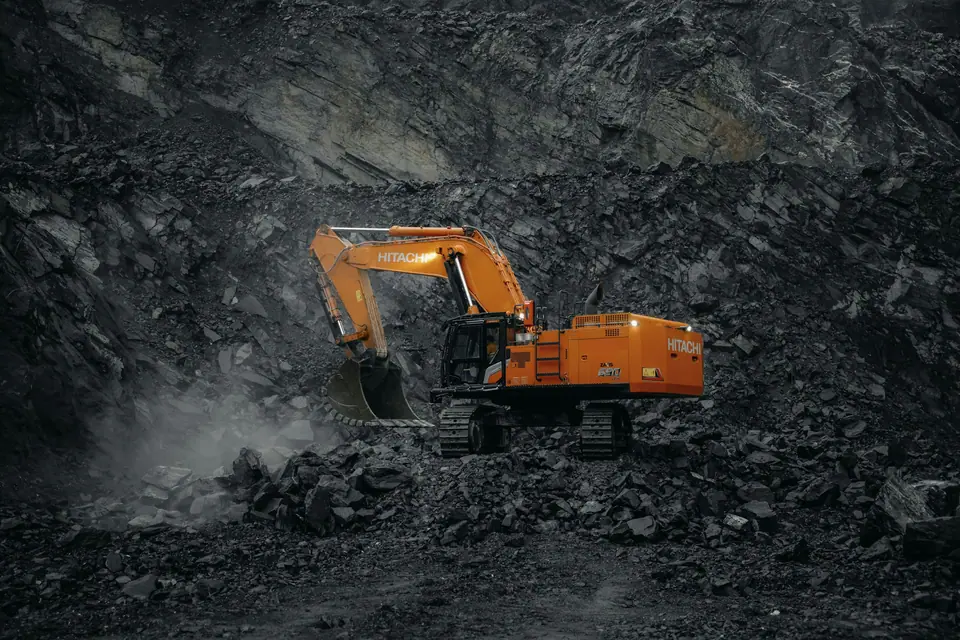 Orange excavator working at a dark coal mine face