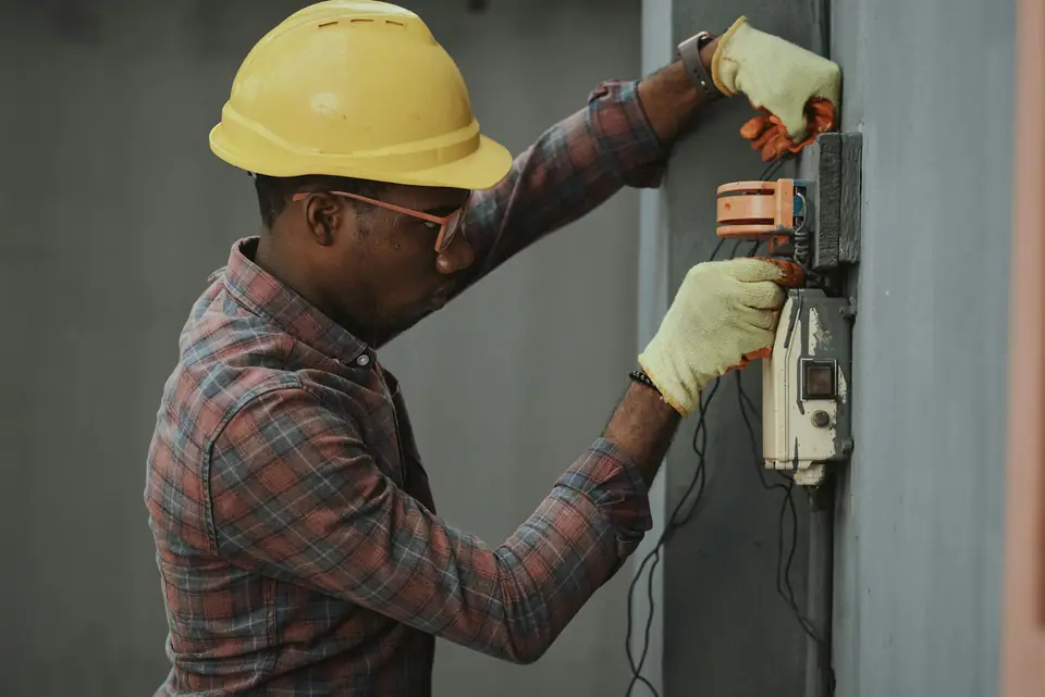 Technician in a hard hat working on an industrial control unit
