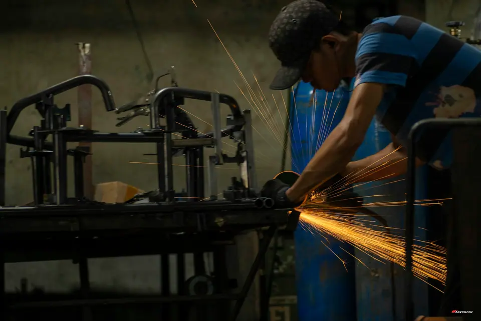 Engineer grinding metal in a workshop with sparks flying